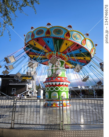 A brightly colored chain carousel in an amusement park against a blue sky A brightly colored chain carousel in an amusement park against a blue sky 134746678