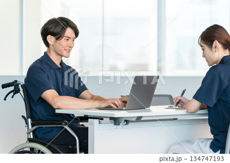 オフィスでデスクワークする車椅子に乗る男性スタッフ オフィスでデスクワークする車椅子に乗る男性スタッフ 134747193