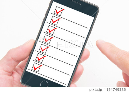 スマートフォンのリストをチェックする人の手元 134749386