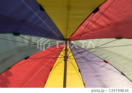 Colorful beach umbrella seen from below creates vibrant abstract patterns for summer holiday promotions Colorful beach umbrella seen from below creates vibrant abstract patterns for summer holiday promotions 134749616