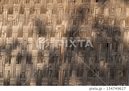 Woven bamboo wall texture with natural shadows creates rustic, organic background design element for craft or sustainable material concept 134749627