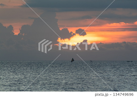Serene sunset over the ocean with sailing boat silhouette and dramatic clouds formation creating peaceful seascape with natural light and copy space Serene sunset over the ocean with sailing boat silhouette and dramatic clouds formation creating peaceful seascape with natural light and copy space 134749696