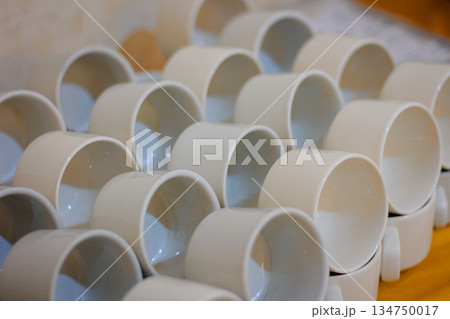 Stacks of Ceramic Cups Arranged Neatly with Soft Natural Light Showing Inner Depths for Beverage or Industrial Use Stacks of Ceramic Cups Arranged Neatly with Soft Natural Light Showing Inner Depths for Beverage or Industrial Use 134750017
