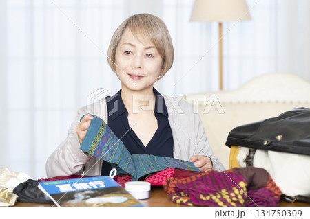 リビングで旅行の荷造りをするシニア女性 134750309