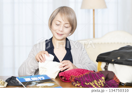 リビングで旅行の荷造りをするシニア女性 134750310