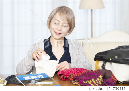 リビングで旅行の荷造りをするシニア女性 134750311