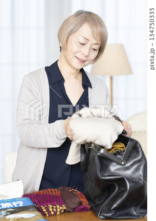 リビングで旅行の荷造りをするシニア女性 134750335