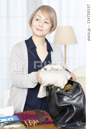 リビングで旅行の荷造りをするシニア女性 リビングで旅行の荷造りをするシニア女性 134750337