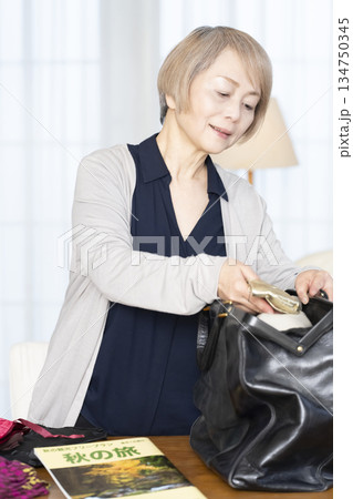 リビングで旅行の荷造りをするシニア女性 リビングで旅行の荷造りをするシニア女性 134750345