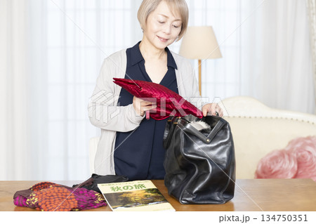 リビングで旅行の荷造りをするシニア女性 リビングで旅行の荷造りをするシニア女性 134750351