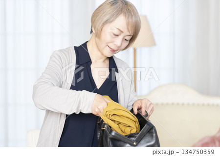 リビングで旅行の荷造りをするシニア女性 リビングで旅行の荷造りをするシニア女性 134750359