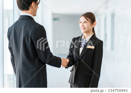 企業のオフィスで握手をして挨拶・自己紹介・契約を結ぶビジネスマン男女 企業のオフィスで握手をして挨拶・自己紹介・契約を結ぶビジネスマン男女 134750943