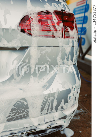 A shiny silver car, thoroughly covered in foam, is undergoing a meticulous cleaning process at an automatic car wash to achieve impeccable cleanliness and a polished appearance that truly stands out A shiny silver car, thoroughly covered in foam, is undergoing a meticulous cleaning process at an automatic car wash to achieve impeccable cleanliness and a polished appearance that truly stands out 134753877