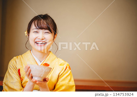 お椀でお茶を飲む若い着物の女性 134753924
