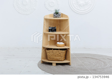 A wooden shelf that features a decorative basket on the bottom shelf A wooden shelf that features a decorative basket on the bottom shelf 134753946