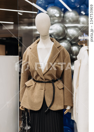 This Fashionable Brown Wool Blazer complete with a stylish Belt is showcased prominently on a Mannequin Display located within a Trendy Boutique Setting, perfect for the fashion enthusiast 134753969