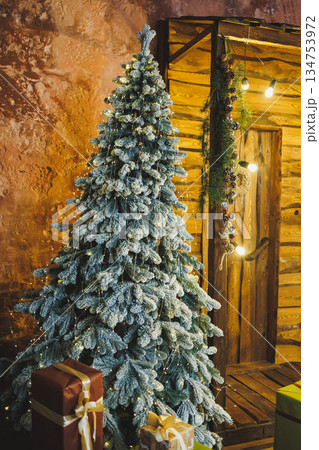 Enter a Winter Wonderland with a snowdusted Christmas tree and shimmering ornaments, surrounded by delightful gifts in a rustic setting, embodying the holiday spirit and inviting joyful celebrations 134753972