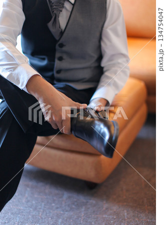 Professional business man tying to put on the dress shoes. A professional, stylish business setting with emphasis on detail and refinement of a fine gentlemen Professional business man tying to put on the dress shoes. A professional, stylish business setting with emphasis on detail and refinement of a fine gentlemen 134754047