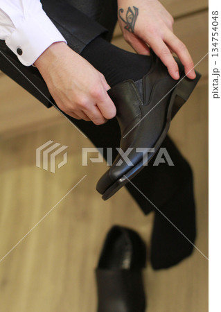 Professional business man tying to put on the dress shoes. A professional, stylish business setting with emphasis on detail and refinement of a fine gentlemen Professional business man tying to put on the dress shoes. A professional, stylish business setting with emphasis on detail and refinement of a fine gentlemen 134754048
