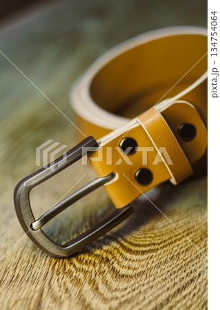 This stylish tan leather belt features a beautiful silver buckle and is displayed elegantly on a rustic wooden surface, making it the perfect fashion accessory suitable for every occasion and outfit 134754064