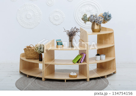 A wooden shelf with a lovely vase of flowers on top 134754156
