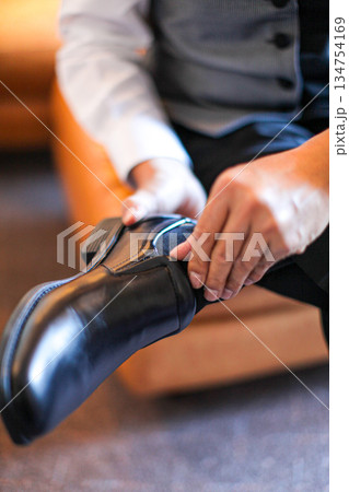 Professional business man tying to put on the dress shoes. A professional, stylish business setting with emphasis on detail and refinement of a fine gentlemen 134754169