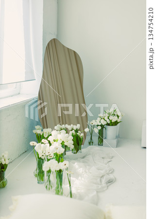This elegantly designed minimalist room features a stunning curved mirror that enhances the space, complemented by fresh white flowers adding a touch of natural freshness to the decor 134754210