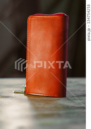 This Elegant Brown Leather Wallet, beautifully placed on a Wooden Table, serves as both a Stylish Accessory for everyday use and a significant Fashion Statement for any discerning individual 134754258