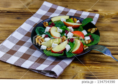 Autumn spinach salad with apple, feta cheese, walnut and dried cranberry on wooden table. Healthy vegetarian food 134754390
