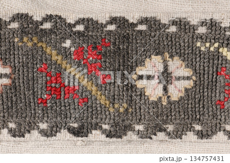 Dark grey woven fabric texture with red and white geometric embroidery Dark grey woven fabric texture with red and white geometric embroidery 134757431
