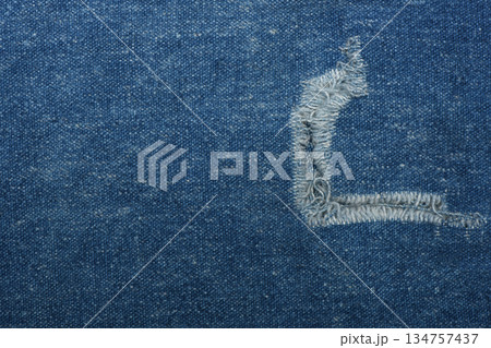 Ripped blue hipster jeans material. Destroyed denim Cloth texture. Close up. 134757437