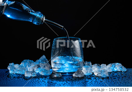 Vodka pours from bottle to glass. 134758532