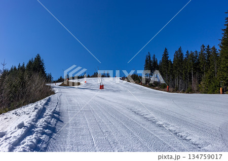 Empty groomed ski slope under a clear blue sky in the mountains. Empty groomed ski slope under a clear blue sky in the mountains. 134759017