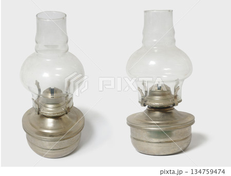 Two vintage oil lamps with glass chimneys and metal bases. Perfect for evoking a sense of nostalgia Two vintage oil lamps with glass chimneys and metal bases. Perfect for evoking a sense of nostalgia 134759474