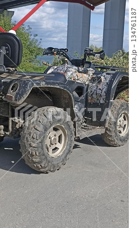 A rugged camouflage all-terrain vehicle (ATV) is covered in mud, indicating recent off-road use. Ideal for outdoor adventures, nature exploration, and recreational activities. A rugged camouflage all-terrain vehicle (ATV) is covered in mud, indicating recent off-road use. Ideal for outdoor adventures, nature exploration, and recreational activities. 134761187