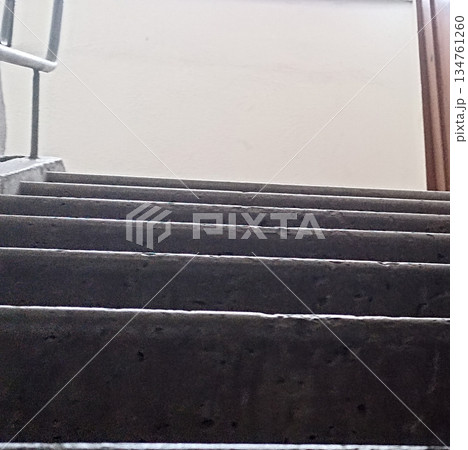 A low-angle view of a gray concrete staircase ascending towards a bright landing. This image symbolizes progress and motivation, perfect for themes of architecture and upward mobility. 134761260