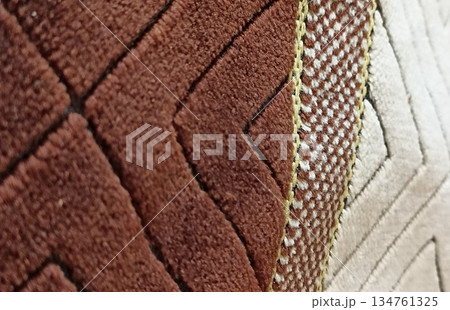 Close-up of a geometric patterned rug in brown, beige, and cream colors. The abstract shapes create a textured design, ideal for backgrounds and interior design projects. 134761325