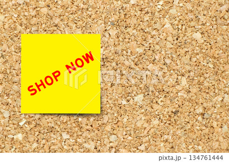 Yellow note paper with word shop now on cork board background with copy space 134761444