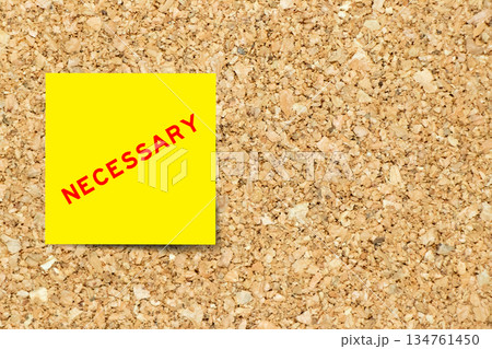 Yellow note paper with word necessary on cork board background with copy space 134761450