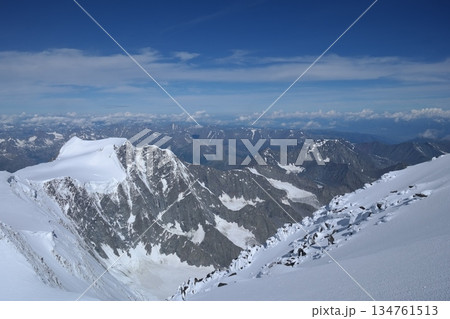 A stunning rock formation covered in snow, set against a clear blue sky with fluffy clouds in the background, creating a peaceful and breathtaking mountain landscape. A stunning rock formation covered in snow, set against a clear blue sky with fluffy clouds in the background, creating a peaceful and breathtaking mountain landscape. 134761513