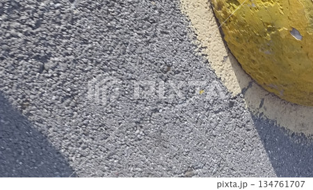 Close-up of asphalt texture featuring a yellow parking bumper. Ideal for backgrounds and design elements related to roads. Perfect for adding visual interest to projects. Close-up of asphalt texture featuring a yellow parking bumper. Ideal for backgrounds and design elements related to roads. Perfect for adding visual interest to projects. 134761707
