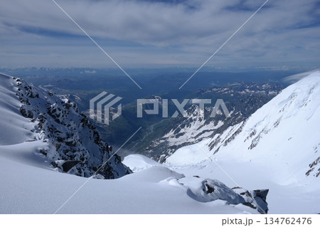A stunning rock formation covered in snow, set against a clear blue sky with fluffy clouds in the background, creating a peaceful and breathtaking mountain landscape. A stunning rock formation covered in snow, set against a clear blue sky with fluffy clouds in the background, creating a peaceful and breathtaking mountain landscape. 134762476