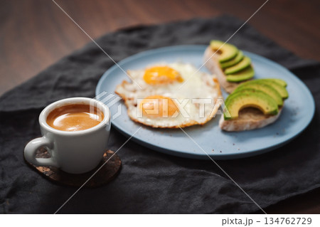 fried egg with two avocado sandwiches and espresso for breakfast on a blue plate fried egg with two avocado sandwiches and espresso for breakfast on a blue plate 134762729