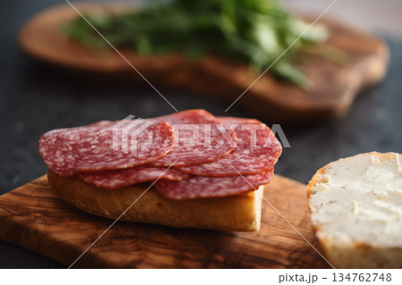 Toasted ciabatta with salami sausage on olive board 134762748