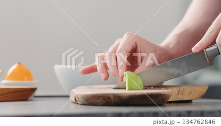 Man slicing ripe avocado on kitchen countertop side view Man slicing ripe avocado on kitchen countertop side view 134762846