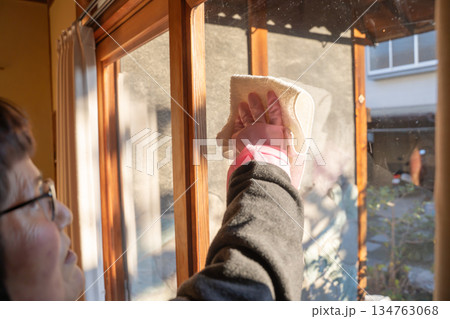 窓拭き掃除をする高齢女性 窓拭き掃除をする高齢女性 134763068