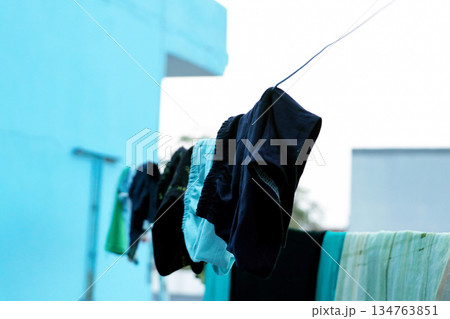 Clothes Drying on a Rope Against Blue Wall Outdoors 134763851