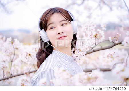 桜の木の下で音楽を楽しむ若い女性 134764930