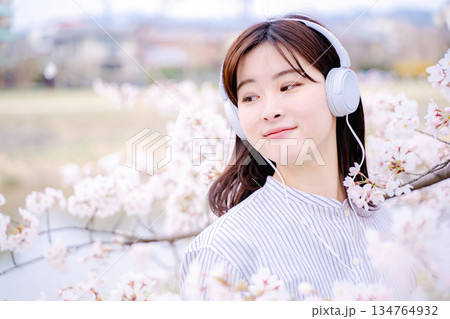 桜の木の下で音楽を楽しむ若い女性 134764932