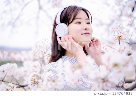 桜の木の下で音楽を楽しむ若い女性 桜の木の下で音楽を楽しむ若い女性 134764935